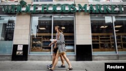 지난 28일 미국 뉴욕시 홀푸트 식품점 앞에 포장한 음식을 손에 든 고객이 걸어가고 있다.