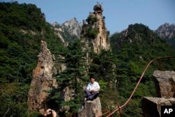 FILE - A North Korean guide poses for photos among the peaks of the Mount Kumgang resort, also known as Diamond Mountain, in North Korea, Sept. 1, 2011. South Korea's Moon Jae-in is look at ways to build relations with North Korea, including resuming tours.