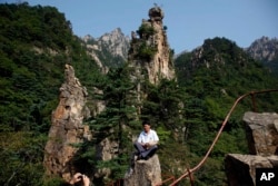 Pemandu Korea Utara berpose di antara puncak resor Gunung Kumgang, juga dikenal sebagai Gunung Berlian, di Korea Utara, 1 September 2011. (Foto: AP)