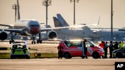 Vehículos de emergencia y coches de policía se encuentran en una pista del aeropuerto de Frankfurt, Alemania, el 25 de julio de 2024. Activistas climáticos se pegaron al suelo bloqueando el tráfico aéreo durante varias horas.