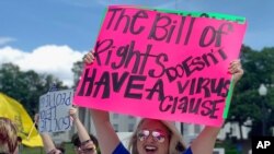 FILE - Kimmy Tillery, a hair dresser from Tuscaloosa, Ala., holds a sign during a protest to reopen Alabama's economy outside the Capitol in Montgomery, Ala., April 21, 2020. 