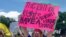 FILE - Kimmy Tillery, a hair dresser from Tuscaloosa, Ala., holds a sign during a protest to reopen Alabama's economy outside the Capitol in Montgomery, Ala., April 21, 2020. 