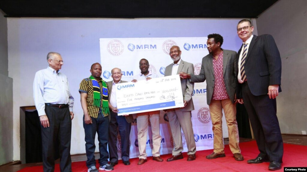 Mshindi wa tuzo ya Kiswahili ya Mabati-Cornell Dotto Rangimoto akipokezwa hundi kutoka kwa Dkt. Willy Mutunga, aliyekuwa Jaji Mkuu nchini Kenya. Alhamisi 15, 2018.