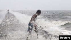 A boy searches for reusable plastic bottles while being pelted by waves brought by typhoon Koppu in Manila Bay October 18, 2015. 