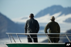 President Barack Obama, accompanied by a National Park Service employee looks at Bear Glacier, which has receded 1.8 miles in approximately 100 years, while on a boat tour to see the effects of global warming in Resurrection Cove, Sept. 1, 2015.