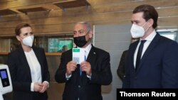 FILE - Then Israeli Prime Minister Benjamin Netanyahu, center, holds up a document, that is part of the "Green Pass" system, which grants certain privileges to citizens who have had both doses of the vaccine against the coronavirus disease (COVID-19).