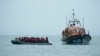 Migrants are helped by RNLI (Royal National Lifeboat Institution) lifeboat before being taken to a beach in Dungeness, on the south-east coast of England, Nov. 24, 2021, after crossing the English Channel.