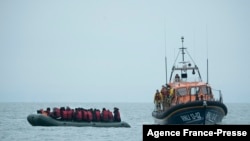 Migrantes são ajudados pela RNLI (Royal National Lifeboat Institution) antes de serem levados para a praia em Dungeness, costa sudeste da Inglaterra, Nov. 24, 2021, depois de atravessarem o Canal da Mancha.