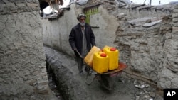 FILE - An Afghan man uses a wheelbarrow to move containers of water in Kabul, Feb. 12, 2018.