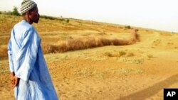 A farmer in Senegal walks across parched land which used to be a riverbed