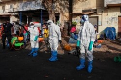 Members of local hygiene services wear protective suits and face masks as they prepare to disinfect the street and market to stop the spread of coronavirus disease (COVID-19) in Dakar, Senegal, March 22, 2020.