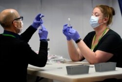 Pharmacy technicians fill syringes with a COVID-19 vaccine at an inoculation site in Portland, Maine, March 2, 2021.