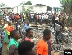 People are seen gathered at the remains of an inn burned down by an angry mob suspecting the inn's owner to be linked to child trafficking, in Kiossi, Cameroon, March 3, 2018. (M. Kindzeka/VOA)