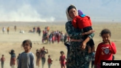 FILE - Displaced Yazidis, fleeing from Islamic State militants, are seen heading toward the Syrian border Aug. 11, 2014.