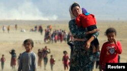 FILE - Displaced Iraqi Yazidis, fleeing from Islamic State militants, head toward the Syrian border Aug. 11, 2014. The Obama administration must determine whether the IS group has been conducting a genocide campaign.