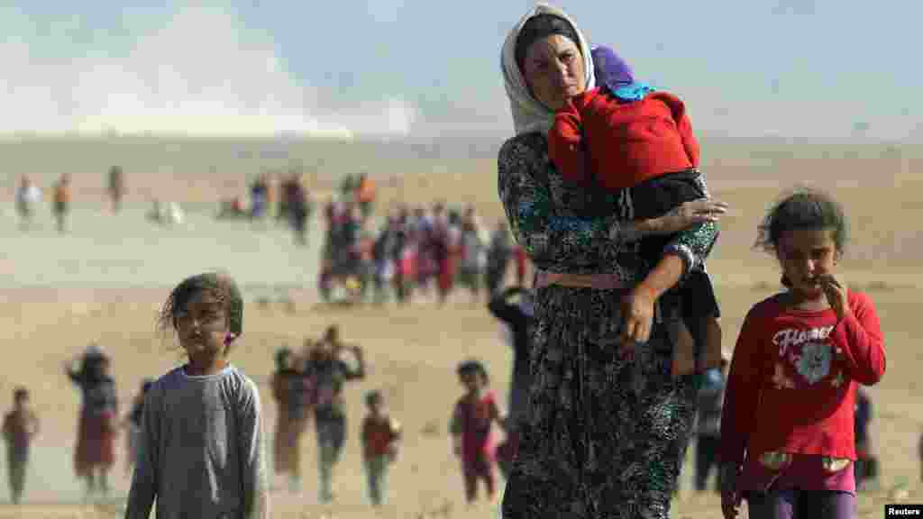 Des personnes déplacées de la secte minoritaire yézidie, fuyant la violence des forces loyales à l'État islamique dans la ville de Sinjar, marchent vers la frontière syrienne, à la périphérie de la montagne de Sinjar, le 11 Août, 2014 .