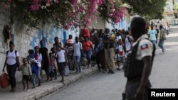 Massa berkerumun pasca pembakaran tersangka anggota geng di salah satu kawasan di Port-au-Prince, Haiti, Senin (24/4). 