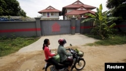 Women ride a motorcycle past a house that is used to temporarily house asylum seekers sent from a Nauru detention center in Phnom Penh, Cambodia, Aug. 31, 2015.