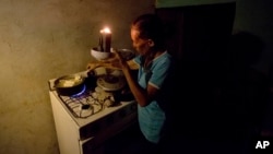 Mireya Marquez uses candlelight to cook her dinner of boiled "cassava," also known as yuca and manioc, Aug. 19, 2018, during a blackout in Maracaibo, Venezuela. For months Maracaibo's residents have endured rolling blackouts, but things turned dire Aug. 10 when a fire destroyed a main power line supplying the city of 1.5 million people.
