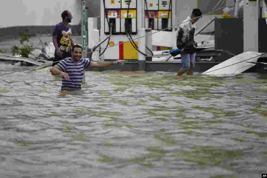 People walk next to a gas station flooded and damaged by the impact of Hurricane Maria, which hit the eastern region of the island, in Humacao, Puerto Rico, Sept. 20, 2017.