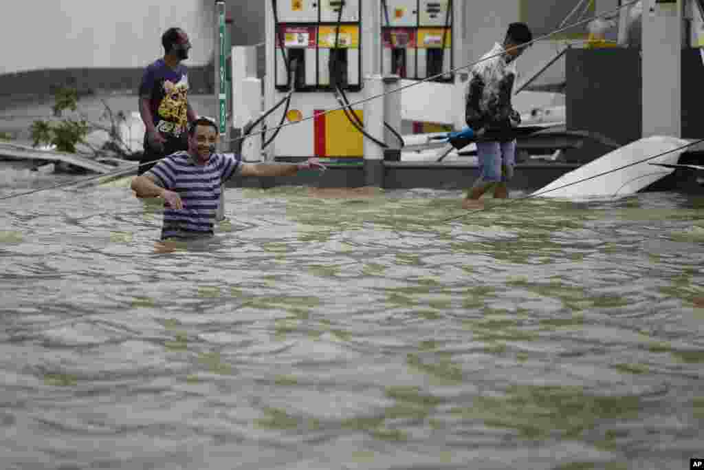 People walk next to a gas station flooded and damaged by the impact of Hurricane Maria, which hit the eastern region of the island, in Humacao, Puerto Rico, Sept. 20, 2017. 