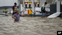 People walk next to a gas station flooded and damaged by the impact of Hurricane Maria, which hit the eastern region of the island, in Humacao, Puerto Rico, Sept. 20, 2017. 