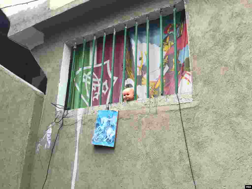 عروسکی پشت میله های پنجره در منطقه ای زاغه نشین در ریو نزدیک ساحل لبنون.