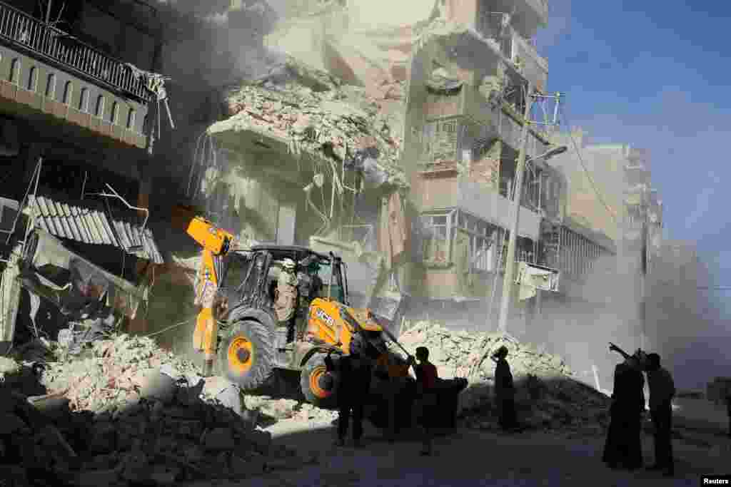 A front loader removes debris in a damaged site after airstrikes on the rebel held Tariq al-Bab neighbourhood of Aleppo, Sept. 24, 2016.