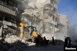 A front loader removes debris at a damaged site after airstrikes on the rebel held Tariq al-Bab neighborhood of Aleppo, Syria, Sept. 24, 2016.
