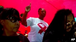FILE - A woman dances as she listens to music while attending a World AIDS Day commemoration at Nkosi's Haven in Johannesburg on Nov. 30, 2019 on the eve of World AIDS Day. (AP Photo/Denis Farrell, File)