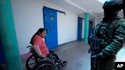 Una mujer presa observa a un soldado que vigila en la cárcel de Cotopaxi durante un recorrido para la prensa organizado por el ejército, el jueves 22 de febrero de 2024, en Latacunga, Ecuador. 