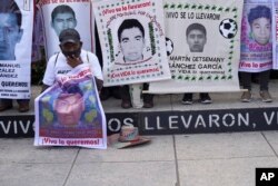 A relative of one of the 43 students who went missing holds a placard with a photo of his loved one, as he joins others in a march on the seventh anniversary of their disappearance, in Mexico City, Sunday, September 26, 2021.