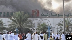 Omani nationals watch smoke rise from Lulu hypermarket in Sohar, February 28, 2011