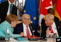 U.S. President Donald Trump and German Chancellor Angela Merkel speak with Tunisian President Beji Caid Essebsi as they attend a round table meeting of G-7 leaders and Outreach partners at the Hotel San Domenico in Taormina, Italy, May 27, 2017.