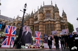 Members of the Anglo-Iranian communities and supporters of the National Council of Resistance of Iran hold a memorial service for British MP David Amess outside the Houses of Parliament in London, Monday, Oct. 18, 2021.