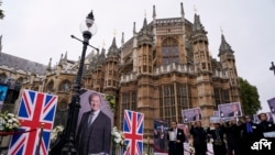 Anggota komunitas Anglo-Iran dan pendukung Dewan Nasional Perlawanan Iran mengadakan upacara peringatan untuk anggota parlemen Inggris David Amess di luar Gedung Parlemen di London, Senin, 18 Oktober 2021. (AP Photo/Alberto Pezzali)
