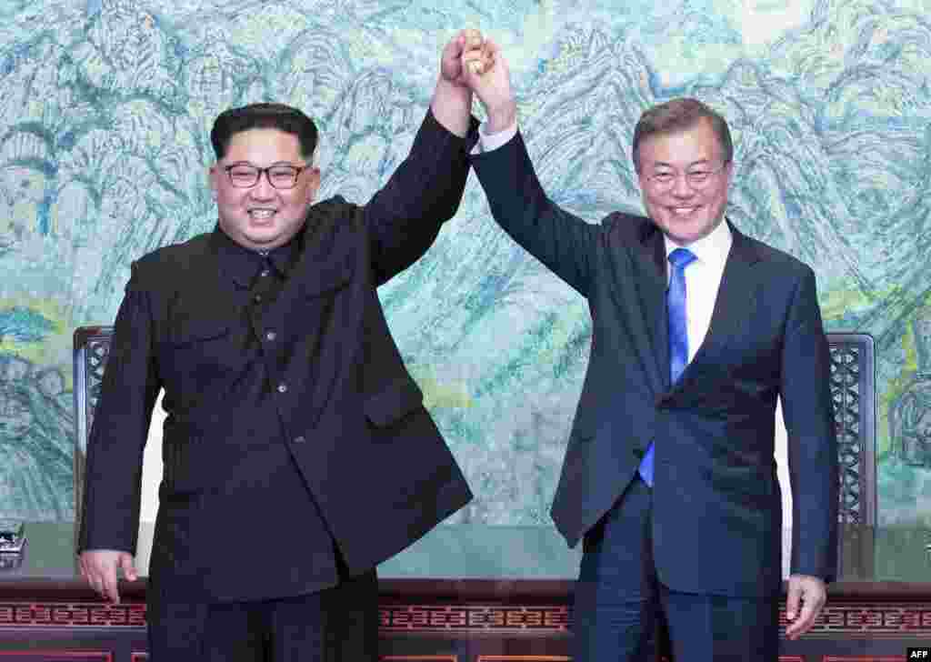 문재인 한국 대통령과 김정은 북한 국무위위원장이 판문점에서 &#39;판문점 선언문&#39;에 서명, 교환한 뒤 손을 맞잡아 들어올리고 있다.