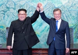 문재인 한국 대통령과 김정은 북한 국무위위원장이 지난 4월 판문점 정상회담에서공동선언문에 서명한 후 맞잡은 손을 들어올렸다.
