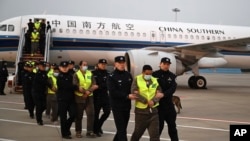 In this photo released by Xinhua News Agency, a group of Chinese citizens suspected of involvement in fraud are escorted by Chinese police after being repatriated from Myanmar via Thailand on arrival at the airport in Nanjing in eastern China's Jiangsu province on Feb. 20, 2025.