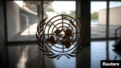 FILE - The United Nations logo is seen on a window in an empty hallway at United Nations headquarters in New York.