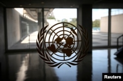 FILE - The United Nations logo is seen on a window in an empty hallway at United Nations headquarters in New York.