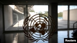 FILE - The United Nations logo is seen on a window in an empty hallway at United Nations headquarters in New York.