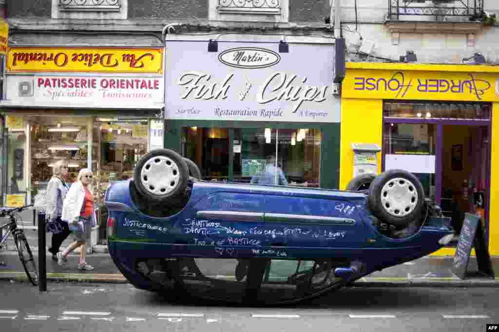 A car is seen parked on its roof in front shops with upside down signs in a street of Nantes, western France, as part of the &quot;A journey to Nantes&quot; (Le Voyage a Nantes) art festival.