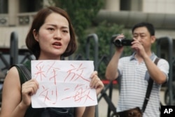 FILE - Li Wenzu, wife of imprisoned lawyer Wang Quanzhang, holds a paper that reads "Release Liu Ermin" as she and supporters of a prominent Chinese human rights lawyer stage a protest outside the Tianjin No. 2 Intermediate People's Court in Tianjin, China, Aug. 1, 2016.