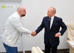 Russian President Vladimir Putin, right shakes hands with the hospital's chief Denis Protsenko during his visit to the hospital for coronavirus patients, March 24, 2020.