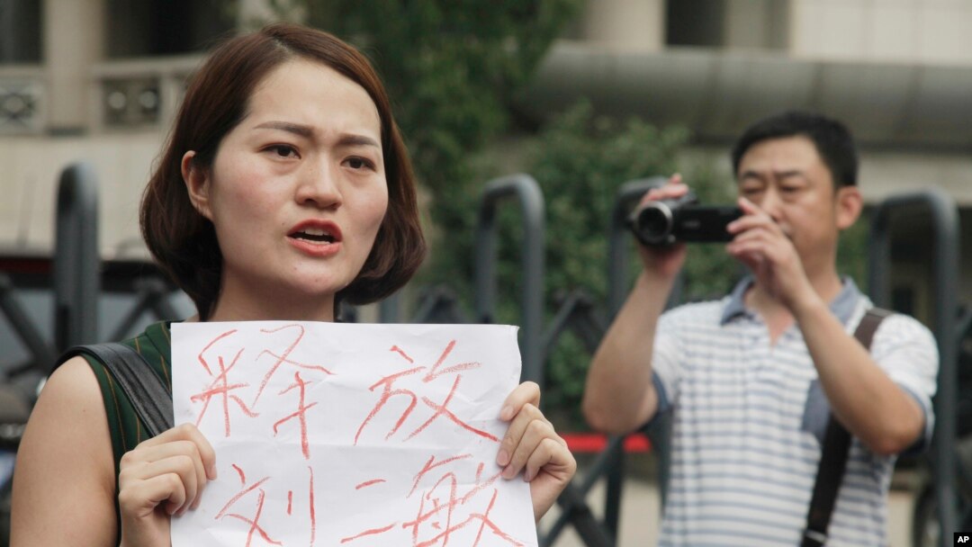 Li Wenzu, istri pengacara HAM China yang sedang dipenjara, Wang Quanzhang, memegang kertas bertuliskan permintaan pembebasan para pengacara, di Tianjin, China. (Foto: Dok)