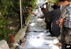 A citizen journalism image provided by the Local Committee of Arbeen shows Syrian citizens trying to identify dead bodies, after an alleged poison gas attack by government forces.