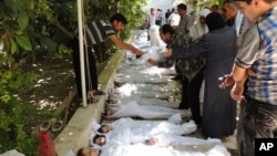 A citizen journalism image provided by the Local Committee of Arbeen which has been authenticated based on contents and AP reporting, shows Syrian citizens trying to identify dead bodies, after an alleged poison gas attack by government forces. There has 