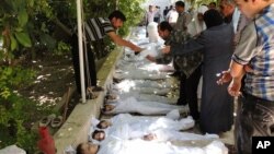 Civilë sirianë përpiqen të identifikojnë trupat e të afërmve. Fotoja është marrë nga një banor, ofruar nga Komisioni Lokal Arbeen. Vërtetësia e fotos është konfirmuar nga materiale të agjencisë së lajmeve Associated Press. 