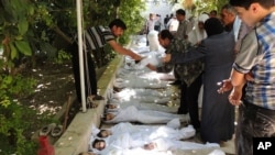 A citizen journalism image provided by the Local Committee of Arbeen which has been authenticated based on contents and AP reporting, shows Syrian citizens trying to identify dead bodies, Aug. 21, 2013, after an alleged poison gas attack by government forces.